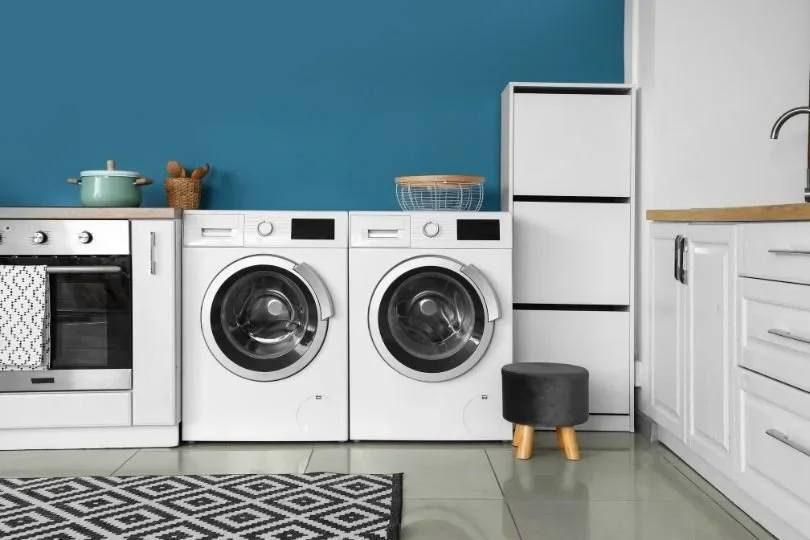 Laundry design inspiration showing storage and side-by-side appliances
